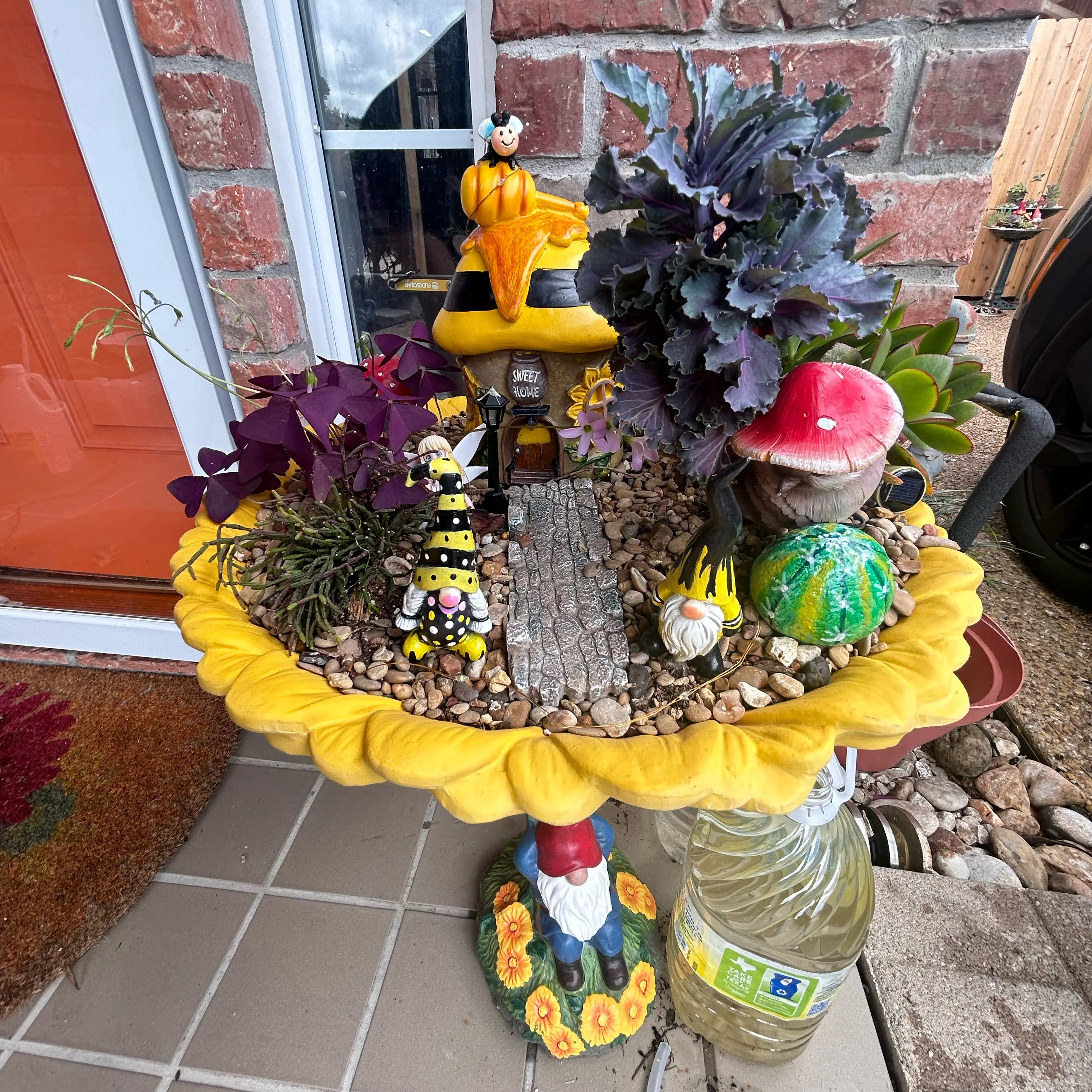 Decorative planter with Crassula capitella 'Campfire' and other plants, adorned with ornaments.