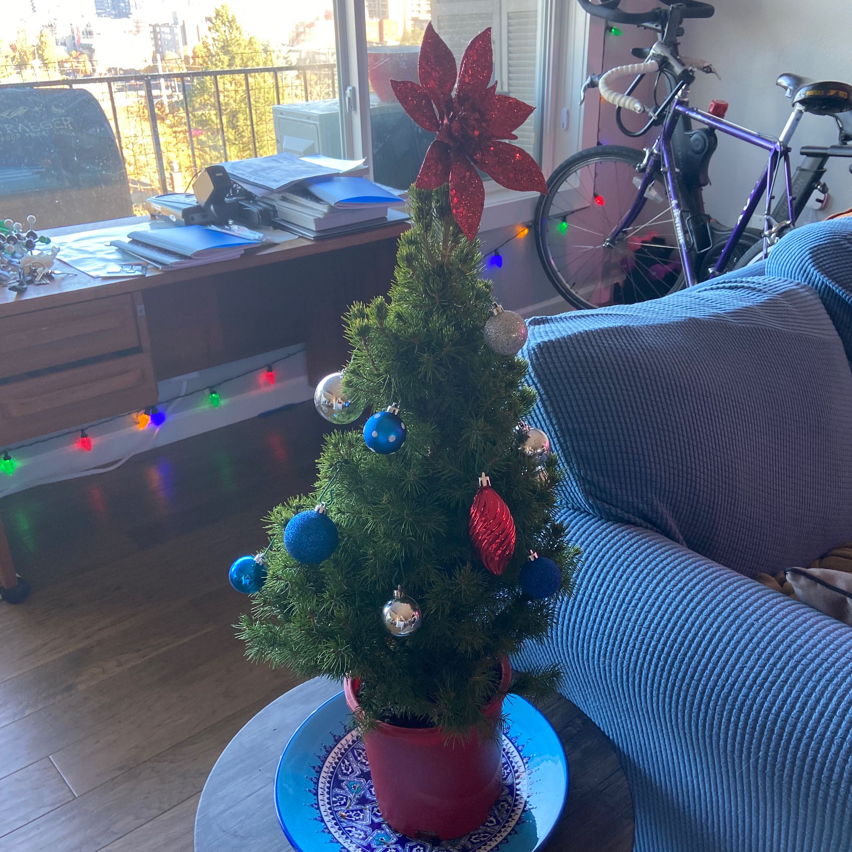 Small Picea glauca plant decorated with ornaments in a red pot.