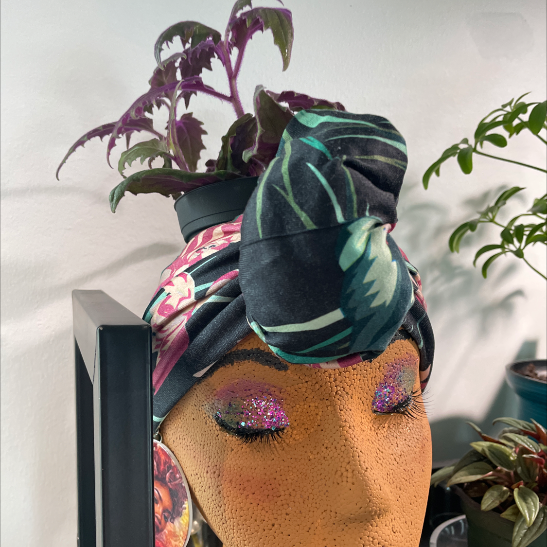 Purple Velvet Plant in a pot on a mannequin head with vibrant purple and green leaves.