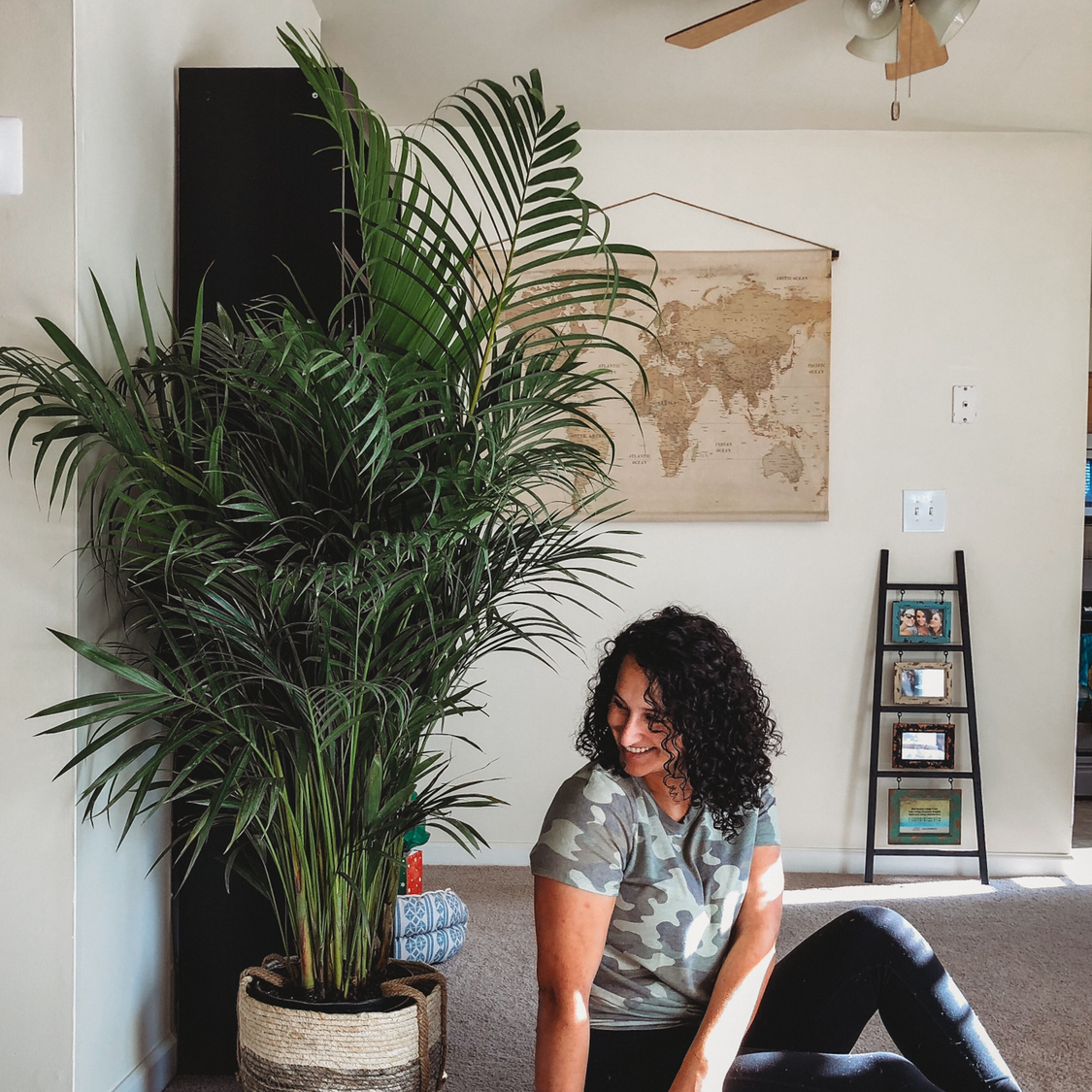 Healthy majesty palm in a basket next to a person smiling. The plant has lush green foliage and appears to be thriving indoors.